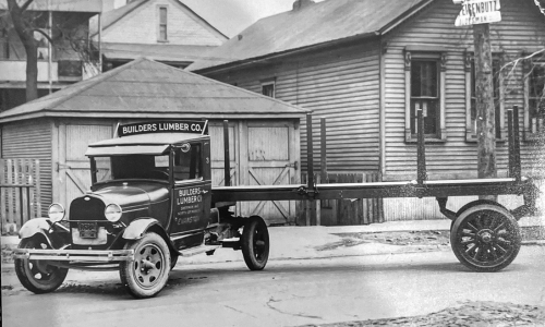 An old photo of Evanston Lumber, in this photo there an old house with an older style truck parked in front.